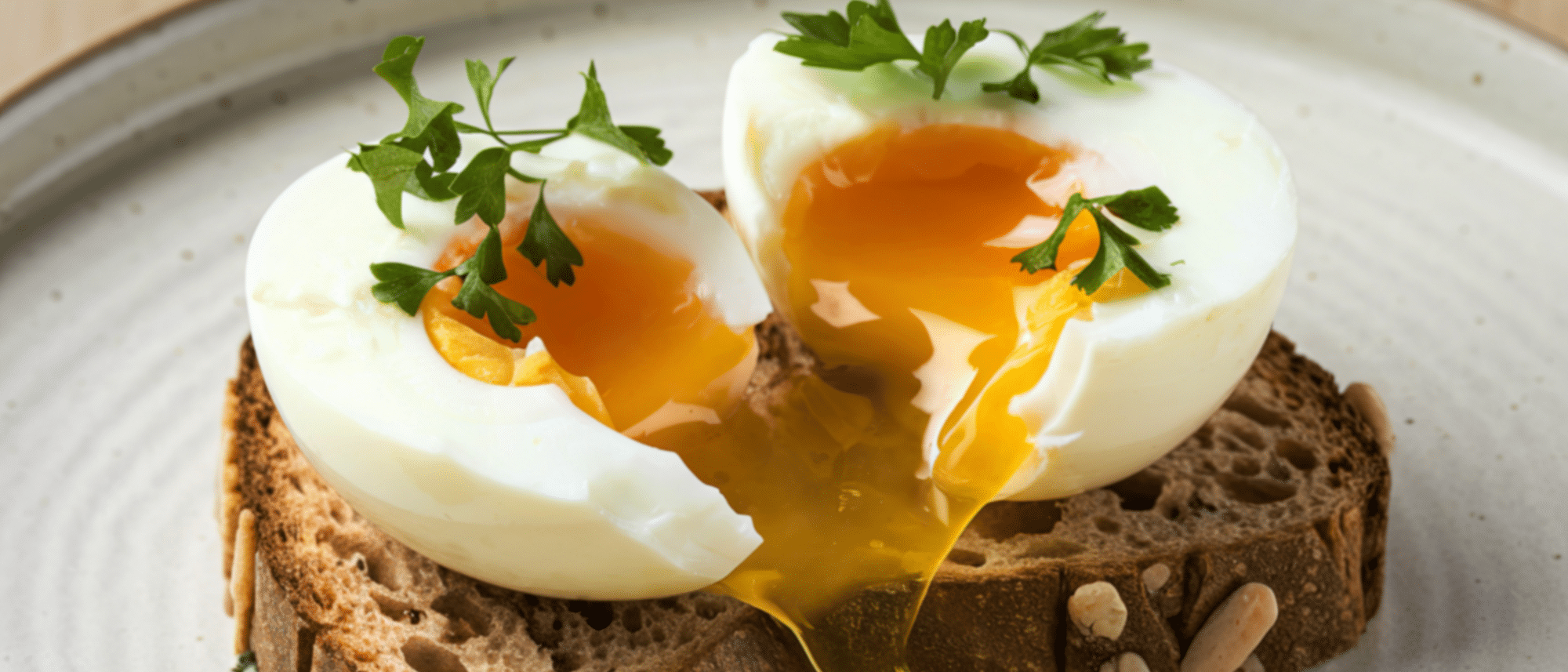 Weichgekochte Eier auf einem Brot, bei denen das Eigelb herausläuft.